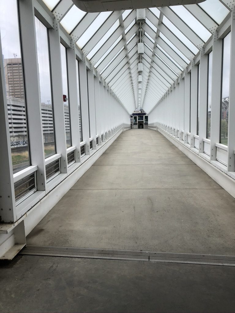 A long walkway with glass walls and concrete floors.