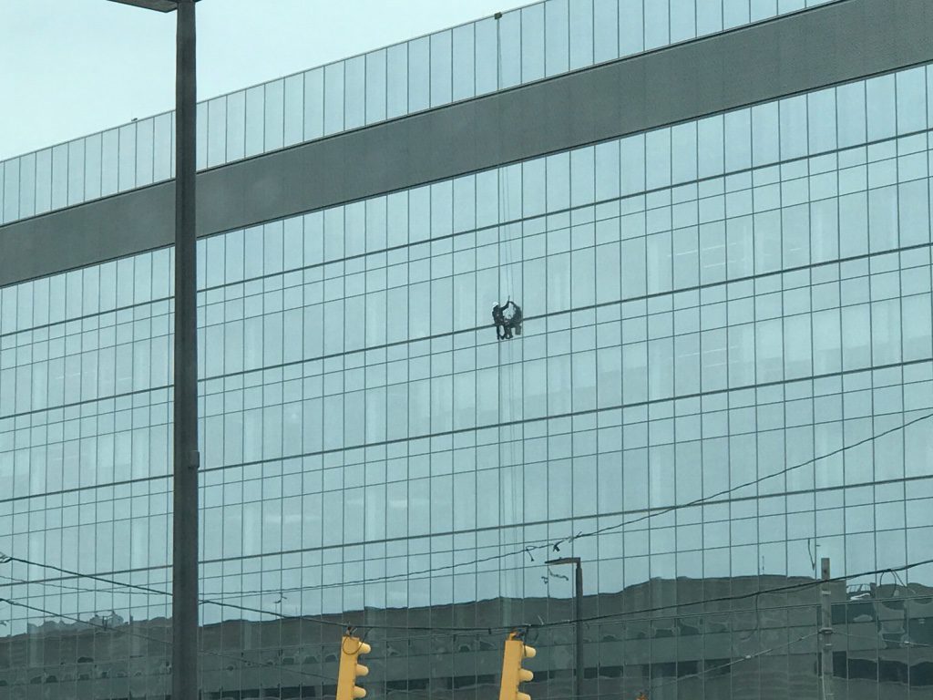 A man is hanging from the side of a building.